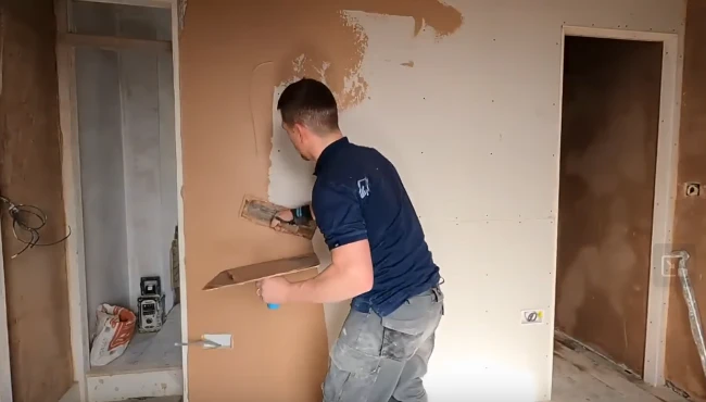 A skilled plasterer skimming an interior wall with a trowel, applying a smooth layer of plaster for a professional finish.