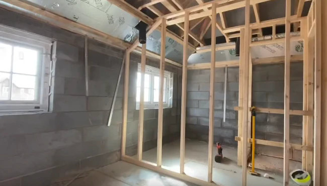 A timber frame first fix partitioning in a house, with two windows in the background and a visible loft, showing the progress in internal construction.